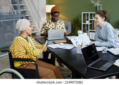 Portrait Of Diverse Creative Team Working In Office With Focus On Young Woman Using Wheelchair At Business Meeting