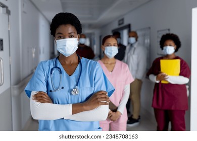 Portrait of diverse female doctors wearing face masks in corridor at hospital. Hospital, hygiene, medicine, teamwork, healthcare and work, unaltered. - Powered by Shutterstock