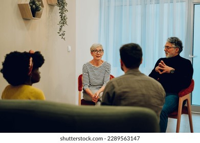 Portrait of a diverse group of patients gathered in circle at psychologist office discussing self problems and sharing points of view while listening others. Focus on a couple of senior people. - Powered by Shutterstock