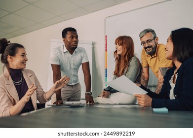 Portrait of a diverse office people group talking and enjoying teamwork during staff meeting. Happy multiracial coworkers have fun working together at office brainstorming. Diversity and inclusivity. - Powered by Shutterstock