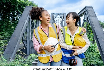 Portrait Diversity Female Engineer Work Together Railway Bridge . Portrait Of Engineer With Green Safety Vest And White Hard Hat At Building Site Looking At Camera.woman Engineering Day.