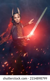 Portrait Of Divine Female Warrior Valkyrie Fighting In A Battle With A Sword In Her Hand. Epic Fantasy. Scandinavian Mythology. Dark Background With Smoke, Sparks Of Fire And Red Light.