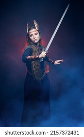 Portrait Of Divine Female Warrior Valkyrie Fighting In A Battle With A Sword In Her Hand. Epic Fantasy. Scandinavian Mythology. Dark Background With Smoke And Red Light.