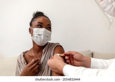 Portrait Of A Doctor Applying A Band Aid After Injecting A Patient In Arm During A Covid Breakdown. Male Hands Putting A Bandage On The Arm Of A Female Patient. Doctor Place A Plaster To His Patient.