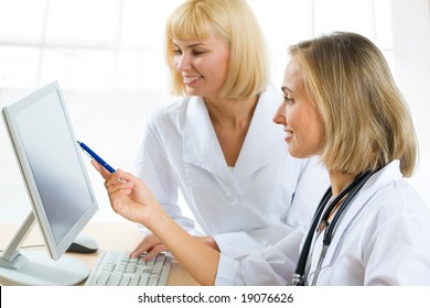 Portrait of doctor explaining computer work to coworker