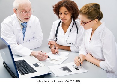 Portrait of doctor explaining computer work to coworkers