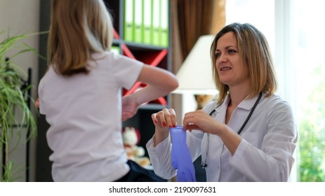 Portrait Of Doctor Helping To Little Kid To Put On Disposable Gloves In Clinic. Pediatrician Medical Services And Healthcare Concept