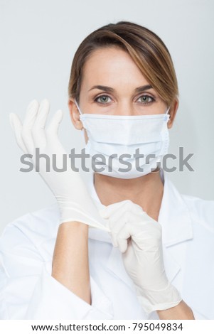 portrait of a doctor with a mask putting latex gloves
