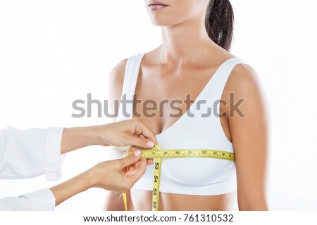 Portrait of doctor with measure tape measuring the size of the patient's breast.