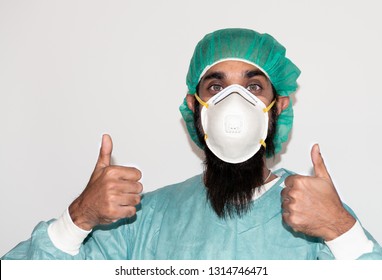 Portrait Of Doctor With Mustache Wearing Hat And Mask N 95,Handsome Bearded Man Is Black Hair And Dark Brown Eyes Wear Green Doctor Uniform And Thump Up With Copy Space,Sikh Man,medical Man