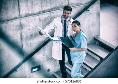 Portrait of doctor and nurse holding medical reports while climbing down stairs in hospital - Powered by Shutterstock