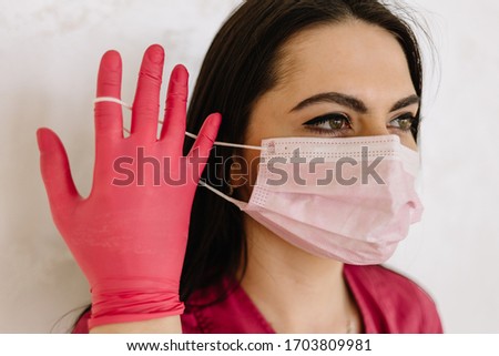 portrait of a doctor putting on a mask and pink uniform. isolated on white background