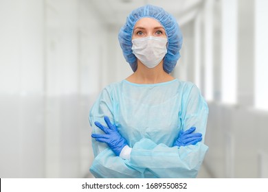 Portrait of doctor in scrubs. A female doctor in a protective cap and face mask in safety measures against the coronavirus. - Shutterstock ID 1689550852