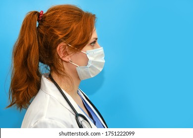 Portrait Of A Doctor Woman In Medical Mask, Closeup. Nurse In A White Uniform And A Protective Mask On A Blue Background, Profile Portrait.