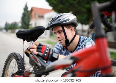 Portrait of down syndrome adult man with bicycle standing outdoors on street, repairing. - Powered by Shutterstock