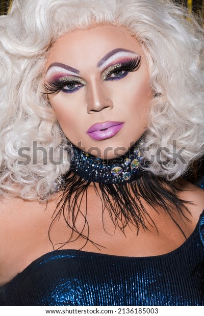 portrait of drag queen with bright makeup, in\
blonde wig and glitter\
necklace