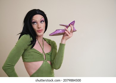 Portrait Of A Drag Queen Person Posing Holding Heels On Beige Background.