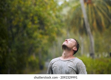 Portrait Of Drenched Man With Eyes Closed Enjoying Heavy Rain In Nature.
