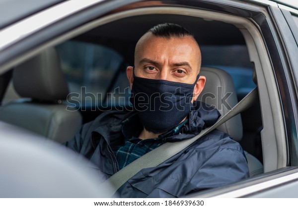 portrait of a driver in a medical\
black mask. looking at the camera. quarantine\
measures