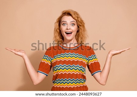 Portrait of ecstatic girl with foxy hairstyle wear t-shirt arms show awesome objects empty space isolated on beige color background