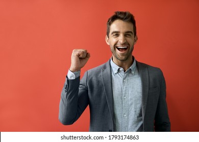 Portrait of a ecstatic young businessman cheering while standing in front of a red background