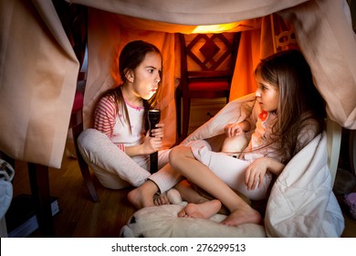 Portrait Of Elder Sister Telling Scary Story To Younger One At Late Night In Bedroom