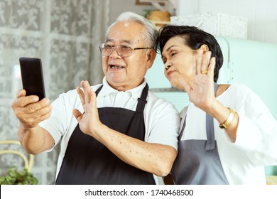 Portrait Of An Elderly Asian Couple Doing Facetime Video Calling With A Smartphone At Home Using The Zoom App, Online Meetings, Social Media, New Normal Concepts