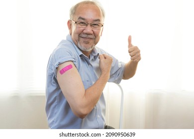 Portrait Of An Elderly Asian Man Smiling After Receiving The Vaccine. A Mature Man Shows His Arm With A Bandage After Full Vaccination.