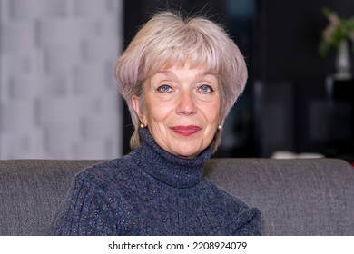 Portrait Of An Elderly Blonde Woman 60-65 Years Old On A Neutral Background In A Room.