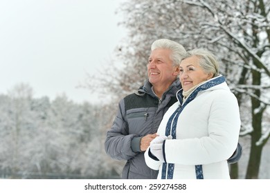 Portrait Of Elderly Couple Having Fun Outdoors In Winter Forest