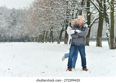 Portrait Of Elderly Couple Having Fun Outdoors In Winter Forest