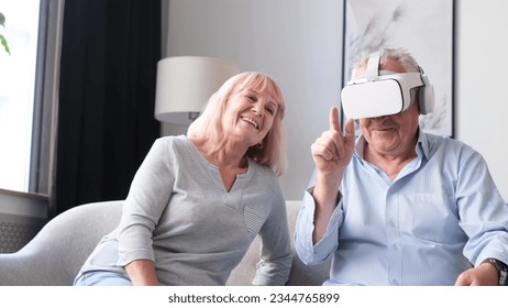 Portrait of elderly couple using virtual reality glasses while sitting in living room. - Powered by Shutterstock