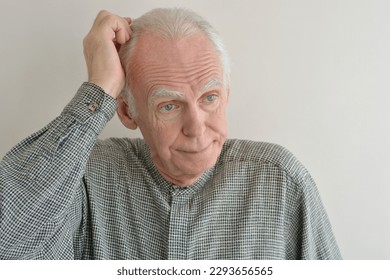 Portrait of an elderly gray-haired man puzzled by the solution of the problem. - Shutterstock ID 2293656565