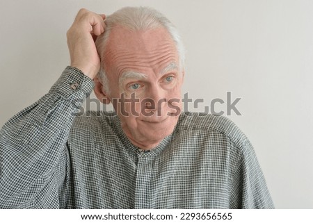 Portrait of an elderly gray-haired man puzzled by the solution of the problem.
