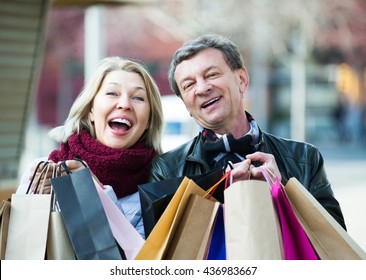 Portrait Of Elderly Happy Couple With Shopping Bags Outdoors