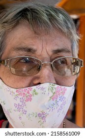 A Portrait Of An Elderly Hispanic Woman With Glasses Wearing Fabric Reusable Face Mask Outdoors On A Sunny Day