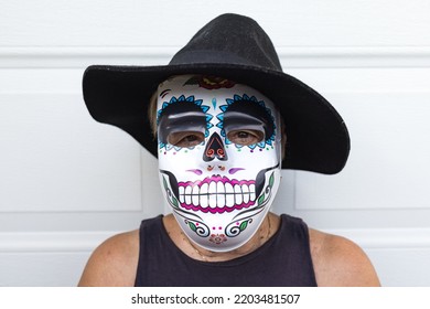 Portrait Of An Elderly Lady With A Catrina Mask And Hat, Celebrating Halloween And All Souls' Day, On A White Background. Celebration, Costume, Party And Mask Concept.