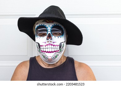 Portrait Of An Elderly Lady With A Catrina Mask And Hat, Celebrating Halloween And All Souls' Day, On A White Background. Celebration, Costume, Party And Mask Concept.