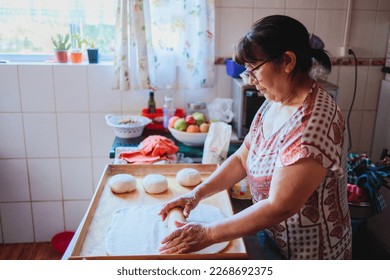 Portrait of an elderly latin woman cooking homemade bread in her kitchen - Shutterstock ID 2268692375