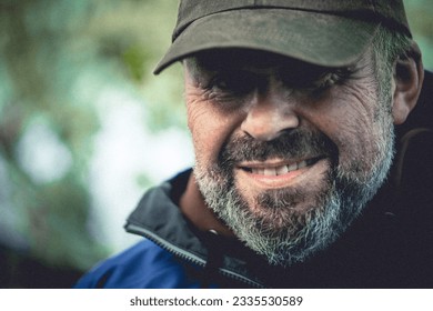 portrait of elderly man with beard and hat. he is out in nature