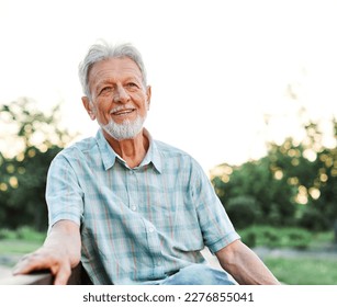 Portrait of an elderly man outdoors. Happy senior man sitting on a bench  in park - Powered by Shutterstock