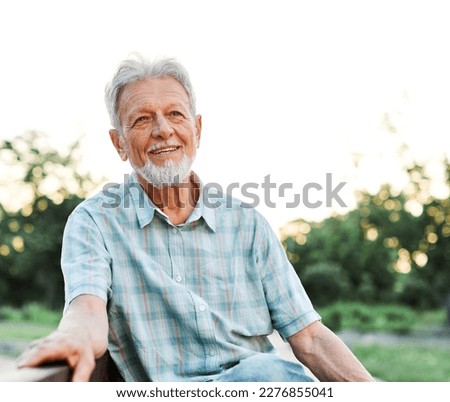 Portrait of an elderly man outdoors. Happy senior man sitting on a bench  in park