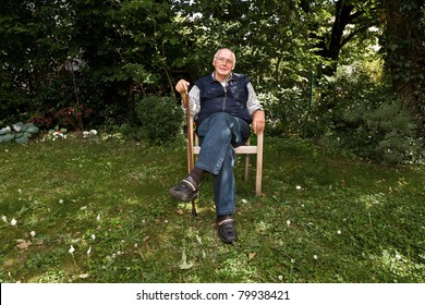 Portrait Of Elderly Man Sitting Happy In His Garden