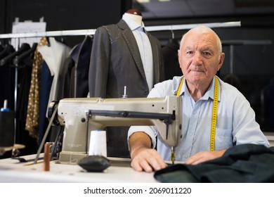 Portrait Of Elderly Man Tailor Working On Sewing Machine At Studio