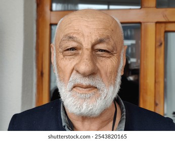 Portrait of an elderly man with a thoughtful gaze, symbolizing wisdom, resilience, and a life full of experiences etched in each line on his face, capturing the dignity and strength of age. - Powered by Shutterstock