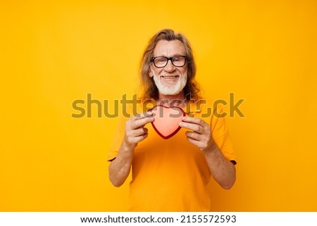 Portrait elderly man yellow t-shirt and glasses posing heart-shaped box cropped view