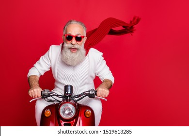 Portrait Of Elderly Modern Person In Eyewear Eyeglasses Driving His Bike Wearing White Sweater Isolated Over Red Background