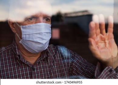 Portrait of elderly senior citizen wearing face mask looking through room window,Coronavirus COVID-19 pandemic outbreak nursing home crisis,high mortality rate and death cases among older population - Powered by Shutterstock