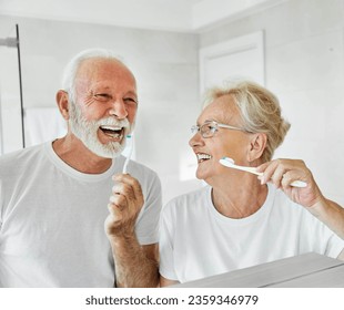 Portrait of an elderly senior couple cleaning brushing their teeth in front of mirror in bathroom. Dental hygiene, vitality, love and beauty concepts - Powered by Shutterstock