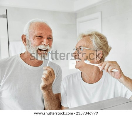 Portrait of an elderly senior couple cleaning brushing their teeth in front of mirror in bathroom. Dental hygiene, vitality, love and beauty concepts